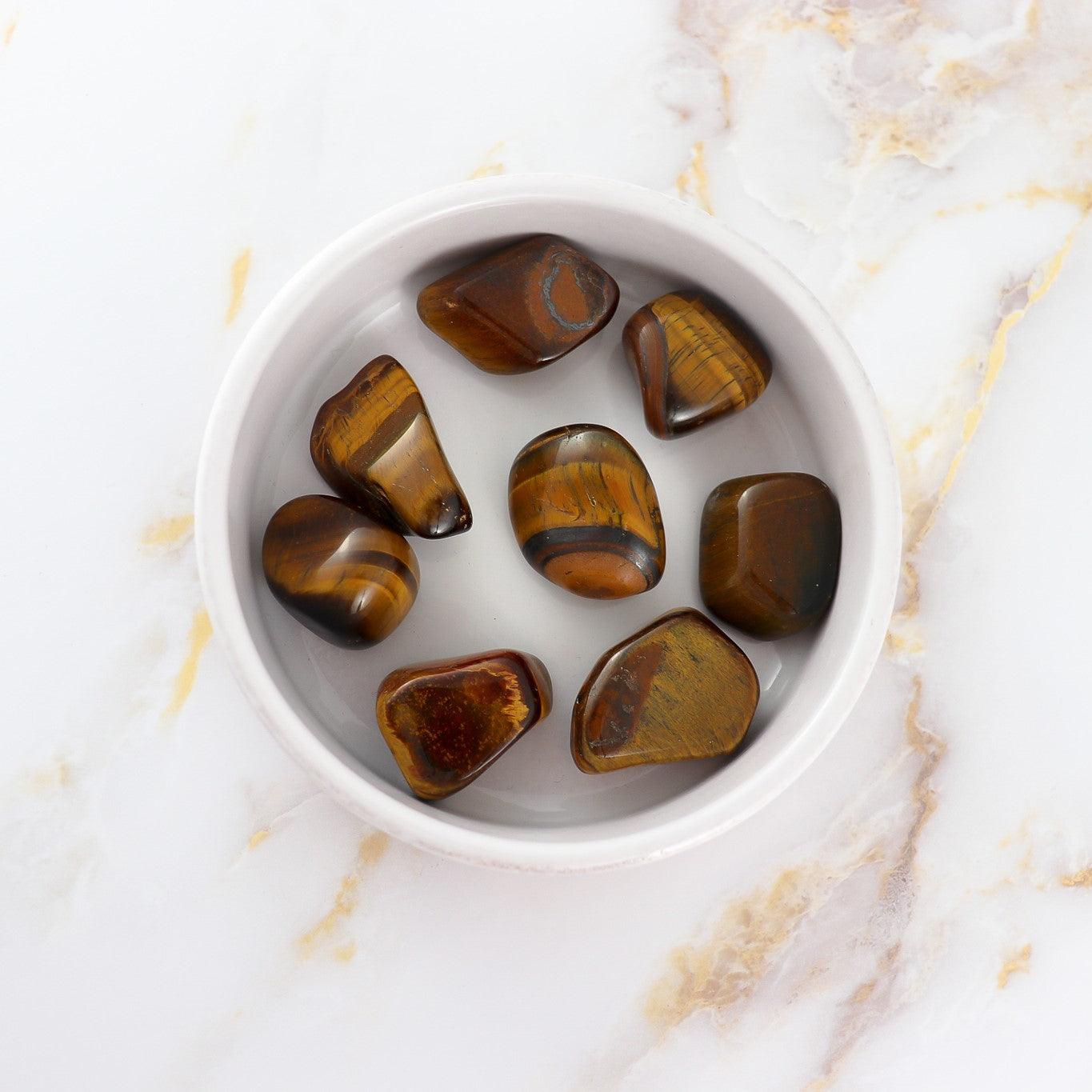 Pierre roulée tigers eye stones polished and displayed in a white bowl by Solstice et Mineraux